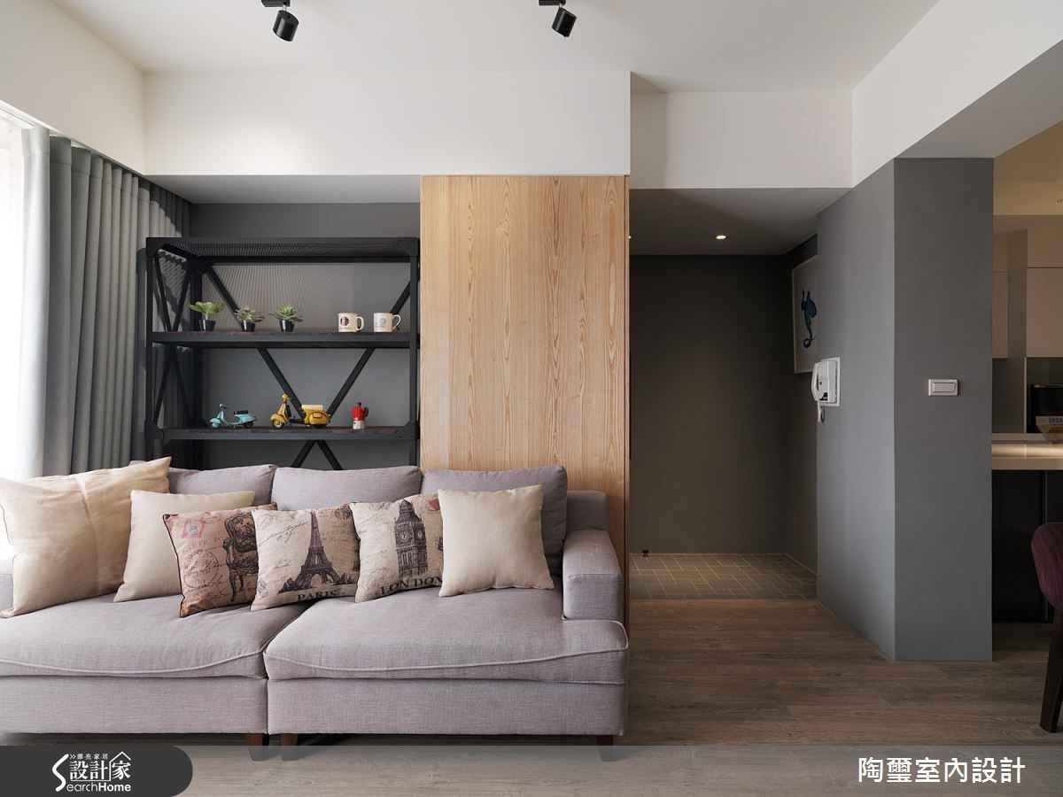 沙發後方的木材質元素乍看之下只是牆面，但其實隱藏了推拉式的鞋櫃，讓收納機能與美感合而為一。
