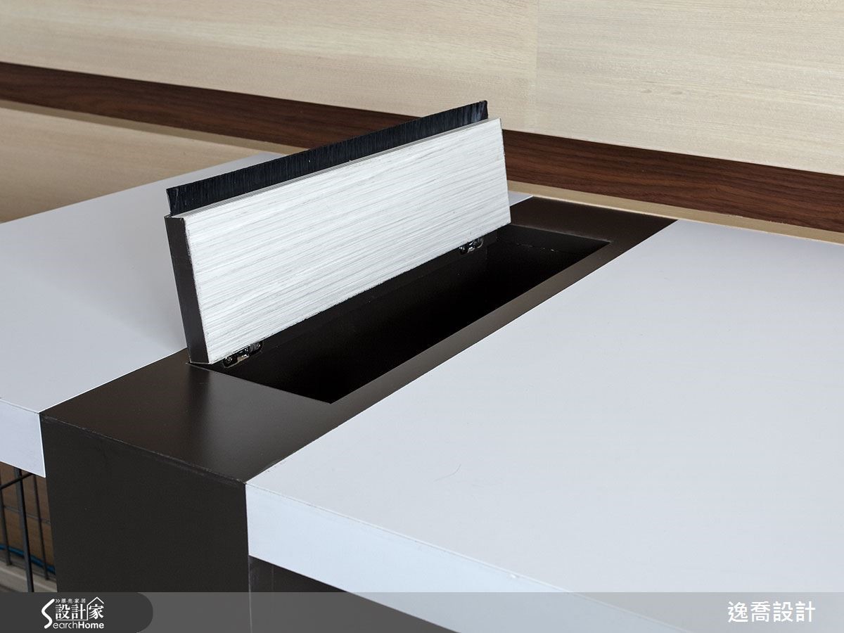 為了讓書桌能與書架層板呼應，設計師加入桌角設計來延伸書桌的長度，同時運用桌腳打造出電器線材收納插座，上方還加入有毛刷條設計的蓋子，讓灰塵不易掉入。