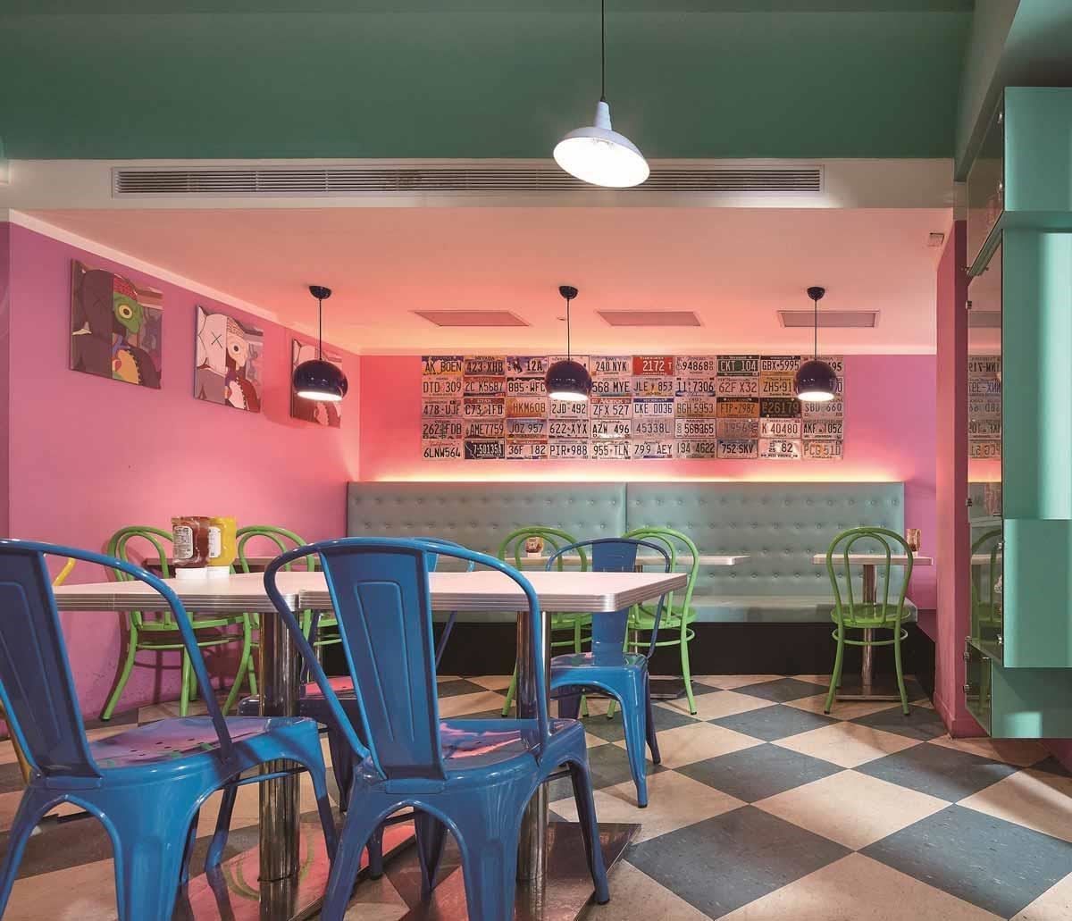 採用藍綠色與白色，加上粉紅色牆面、藍綠色復古皮革沙發，再加上各式鮮豔顏色烤漆的工業風餐椅、吧檯椅，營造摩登、年輕的美式餐廳空間。