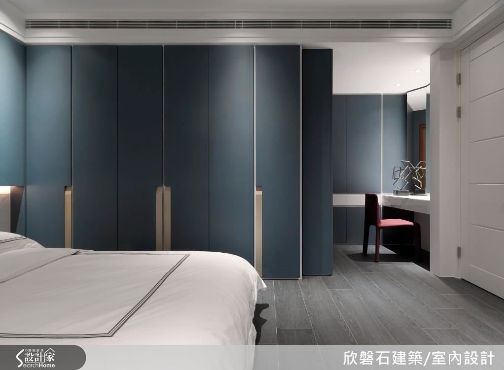 次臥以樑化出小客廳中起居與書房場域，整面白色拉門隱藏了以畸零角落建構的吧檯與收納空間，釋放視覺感受退以室外綠意景致為主角。睡眠區以白色大理石為底衍生懸空床頭櫃，立面承載搭配烤漆金隱藏式把手設計的墨藍色烤漆櫃體，延伸入內，梳妝區以卡拉拉白銀狐石材腰帶設計裝飾，石材導角抽屜與隱藏式鏡子，呈現細緻工藝與色彩的美學構思。