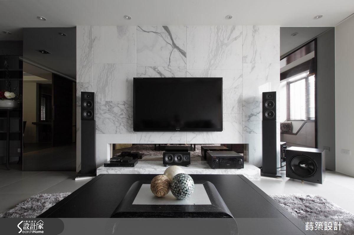 電視牆採用整塊石材切割後，再拼貼而成，因為紋理系出同源，反而比用一整塊石材來得靈活輕盈；左右兩邊以茶鏡裝飾，既可以放大視覺空間，增加光線反射，左邊的一扇同時隱藏1坪大的儲藏室入口，減輕視覺雜亂的機會。