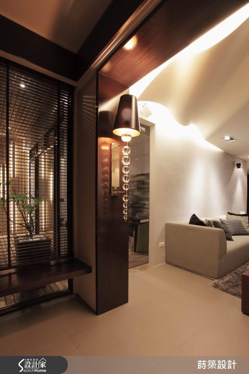 陽台與客廳之間，做出超寬的門框，其實是為了隱藏柱子以及電視牆的機櫃，特別挑選的大型壁燈成為亮眼裝飾，夜幕低垂時，整個空間瀰漫浪漫氣氛。