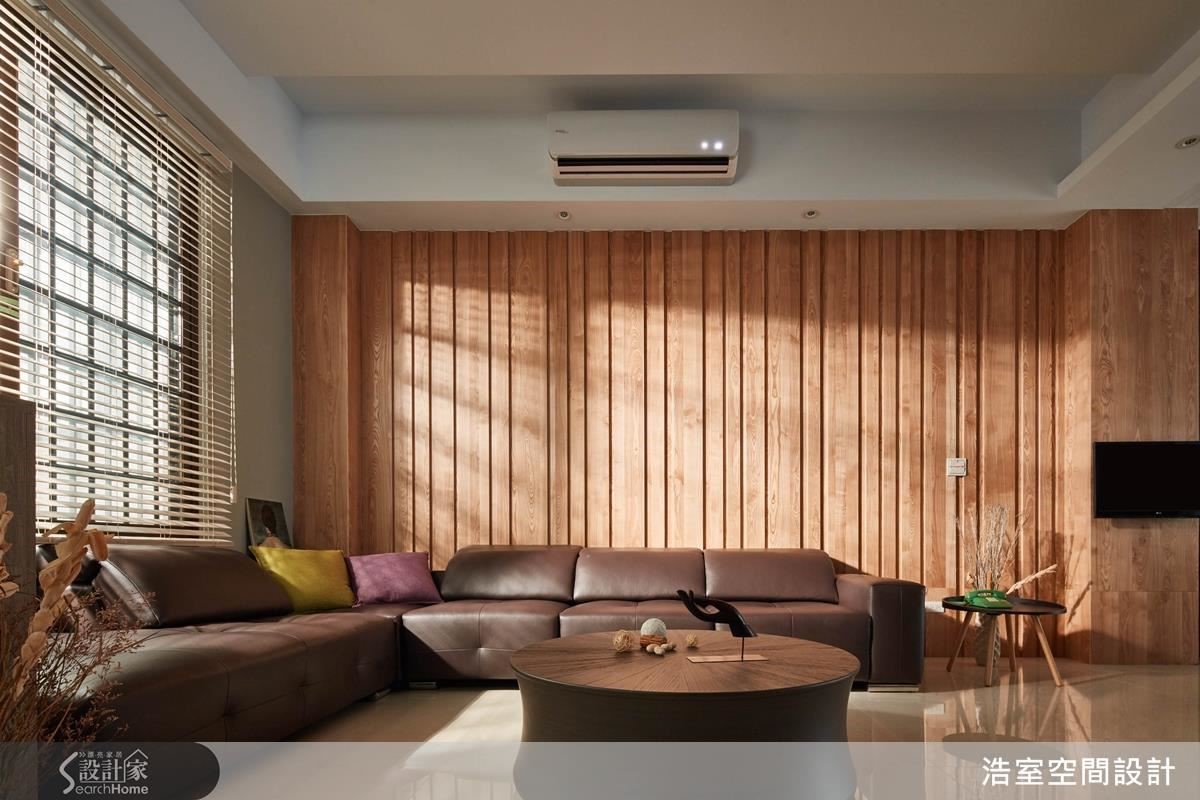 至於靠窗的客廳則是做出粗細不一的溝縫，配合木色及捲簾，反而呈現日式禪風的寧靜感。至於 2 個空間之間的柱子，一樣以實木貼皮工法包覆，嵌上可以移動方向的電視，有串聯與分割空間的意味。