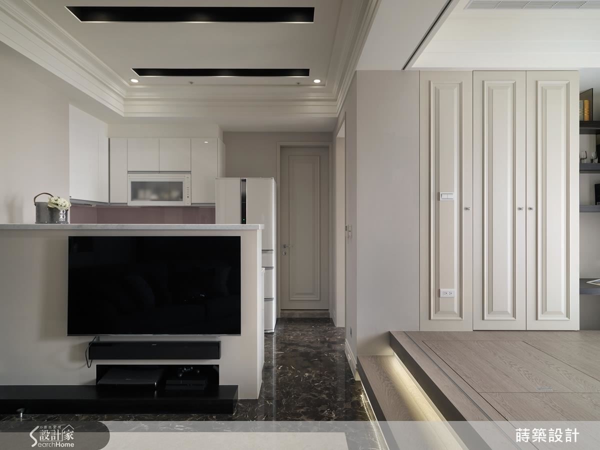 一進門就是客廳，利用廚房的半高吧台當隔間也兼電視牆，走道的寬度剛好增加沙發與電視的距離，又是一地多用的妙招。