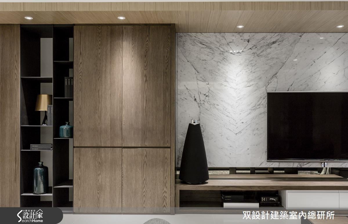 客廳主牆的左半部，運用深色的天然木皮及黑色鐵件打造出虛實交錯的落地櫃格；右半的電視牆，則利用大理石的天然紋理及簡練的底櫃造型來展現精煉的品味。