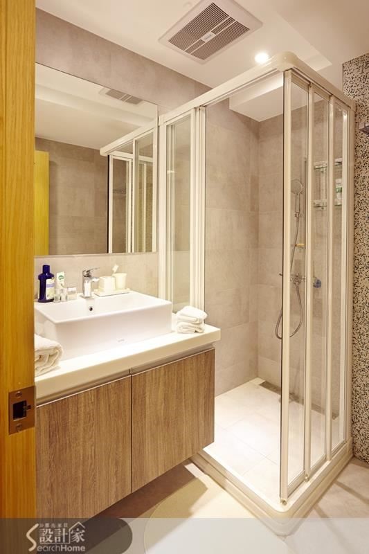 設計師為主臥衛浴間量身製訂了以系統櫃搭配人造石的浴櫃，出品味精煉又有收納機能。淋浴拉門乾濕分離的設計能讓整間浴廁更顯舒爽。