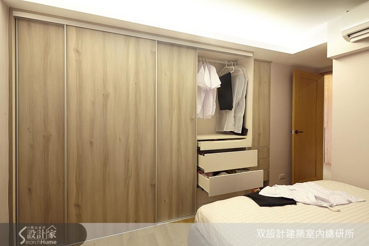 主臥面寬兩米三的大衣櫃整合了抽屜、吊掛衣架與儲物櫃。這道牆面的深度原本不足，略往客廳挪動了 15 公分之後，就能打造整排櫃體了。