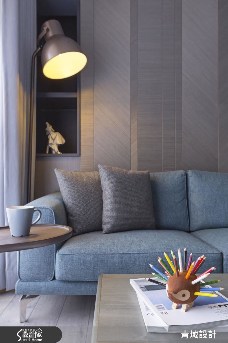 以不同紋路、面積的實木皮拼貼，營造沙發背牆的層次感。角落可放幾本書籍的櫃子前，一盞溫暖黃光灑下的角落，似乎是假日放鬆、閱讀窩躺一整天最棒的地方。