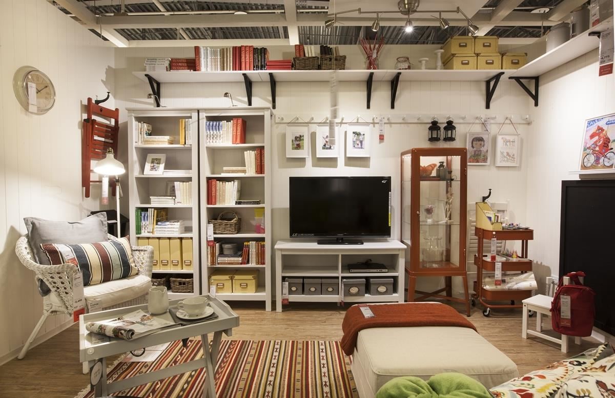 小客廳有著豐富的收納牆面，左半部規劃開放式的收納櫃體，右半部以電視櫃、透明展示櫃與推車混搭組合，上半部運用層架和掛勾增加牆面空間，讓向上發展的牆面有更多收納空間。