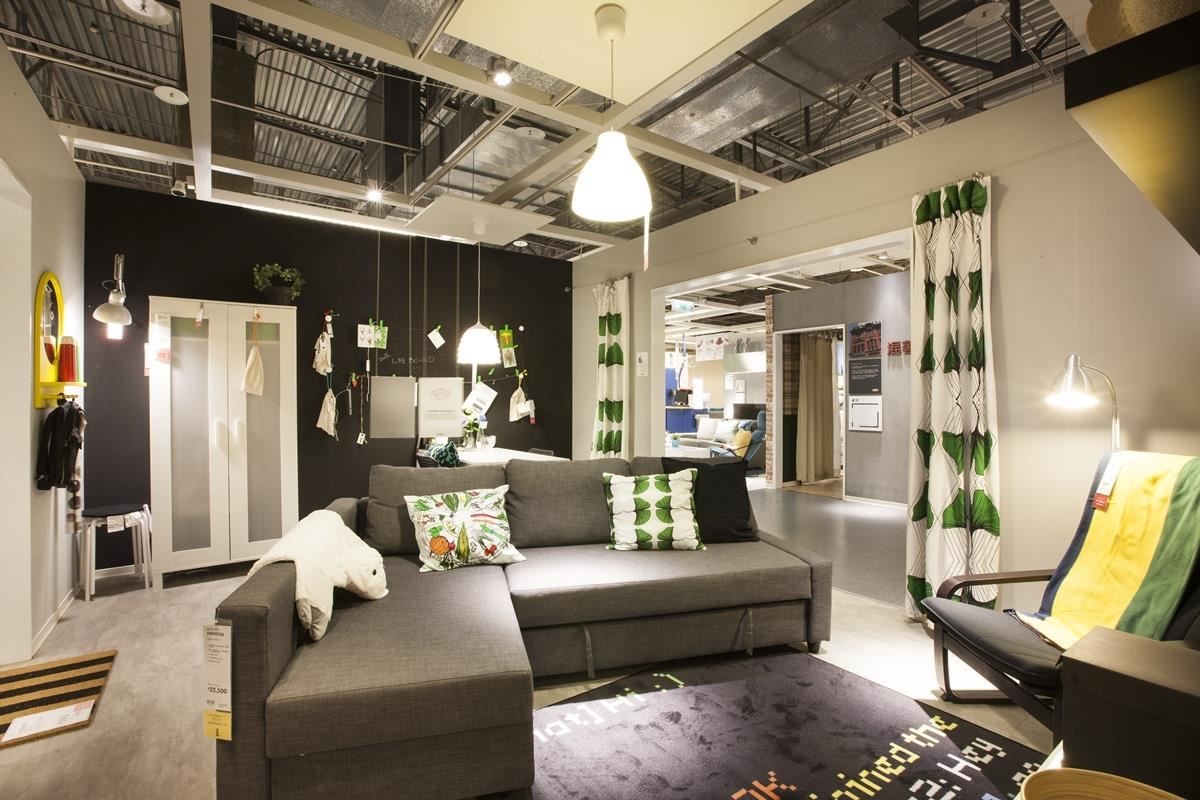 少預算的新手夫妻，選擇以黑灰色的 L 型沙發床呈現居家質感，沙發床擺在客廳正中間，搭配綠色系家飾與窗簾，展現年輕不受拘束的個性。