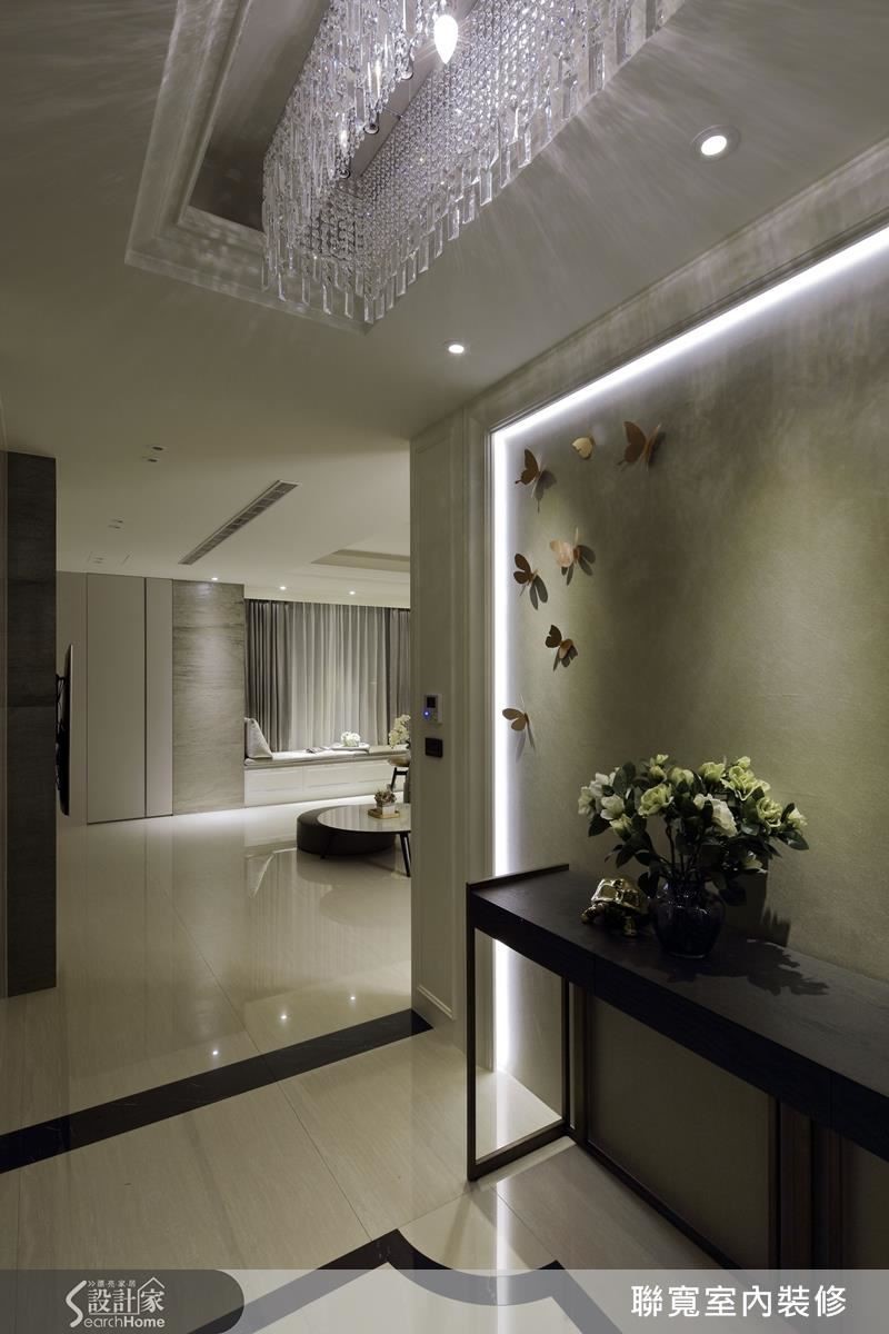 玄關進門處，水晶吊燈映在暖灰的主牆面，搭著象徵家徽的地磚，彷彿告訴你「歡迎回家」。