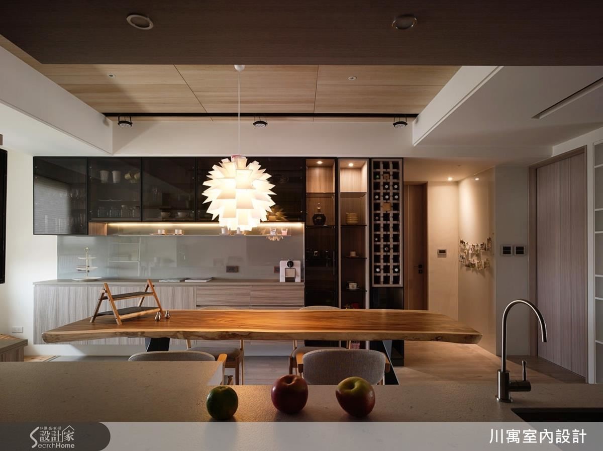 餐桌的另外一面擺放咖啡機、杯盤和酒櫃空間，黑玻櫃體收納看起來簡潔，開啟燈又能轉變成現代時尚的展示櫃。