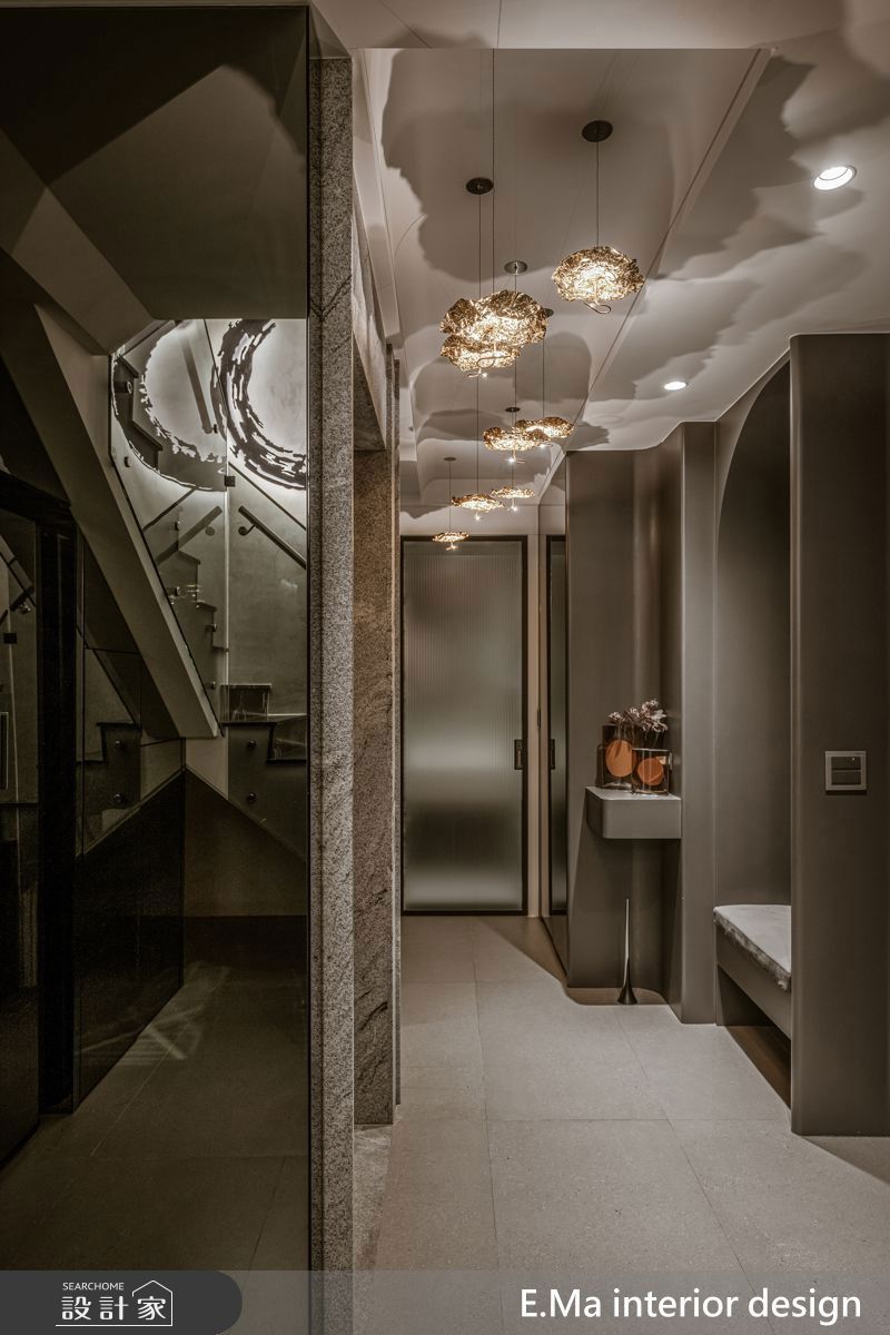 義大利原裝燈具與書法家藝術作品,營造出如藝廊般的玄關層次;玻璃扶手的樓梯則讓上下樓時能相互看見,增加互動。
