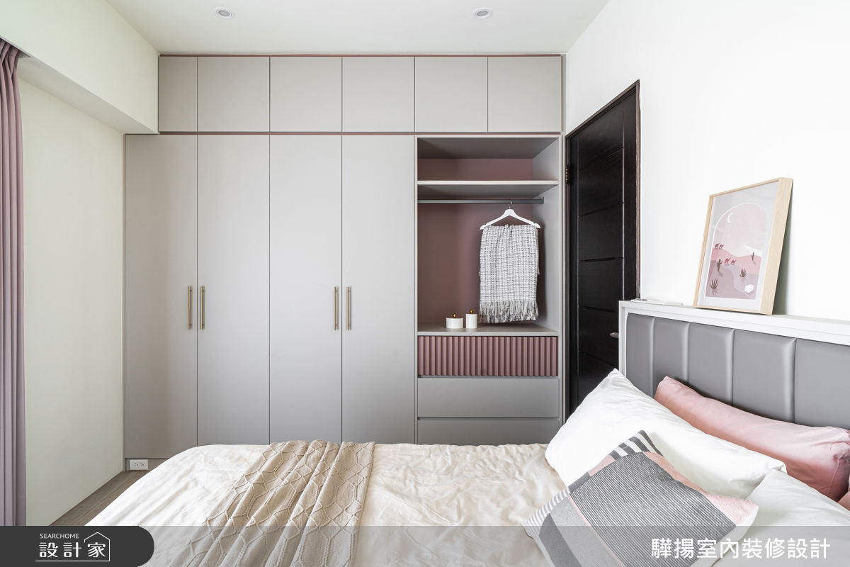 主臥室以灰粉混搭元素妝點，整面衣櫃結合封閉與局部開放設計，讓機能和美感融為一體。