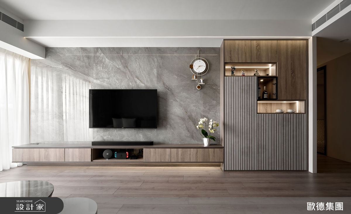 電視牆以深灰大理石鋪陳，紋理細膩沉穩，呈現內斂靜謐的生活氣韻。
