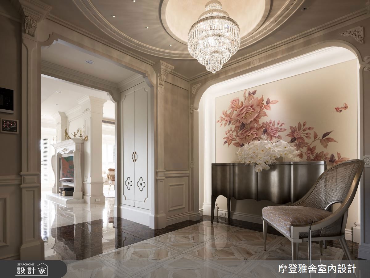 建材的選擇與色調搭配是彰顯屋主美感與品味第一印象，也是設計師的首要任務。以此案為例，納入天圓地方風水概念的二進式玄關，搭配水晶燈、大理石地坪與雕花線板，並以設計師手繪壁布收攏端景，沈穩大器的新古典氣勢立現。