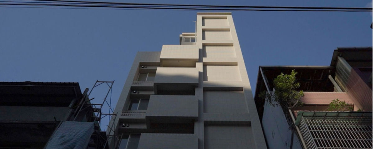 透過危老條例所改建的一棟極其細長的新大樓,矗立在兩棟舊平房之間。