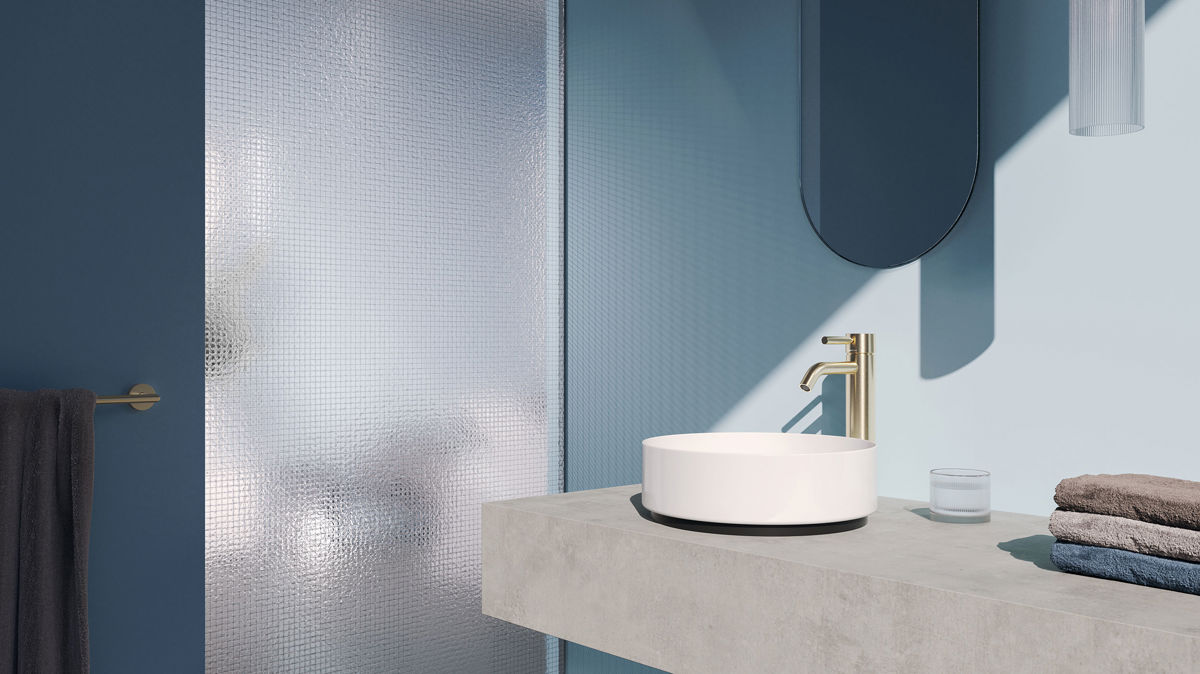 Dornbracht META金色龍頭以俐落圓柱線條佇立檯面，在冷灰石材與霧藍牆面間形成和諧的對比，。