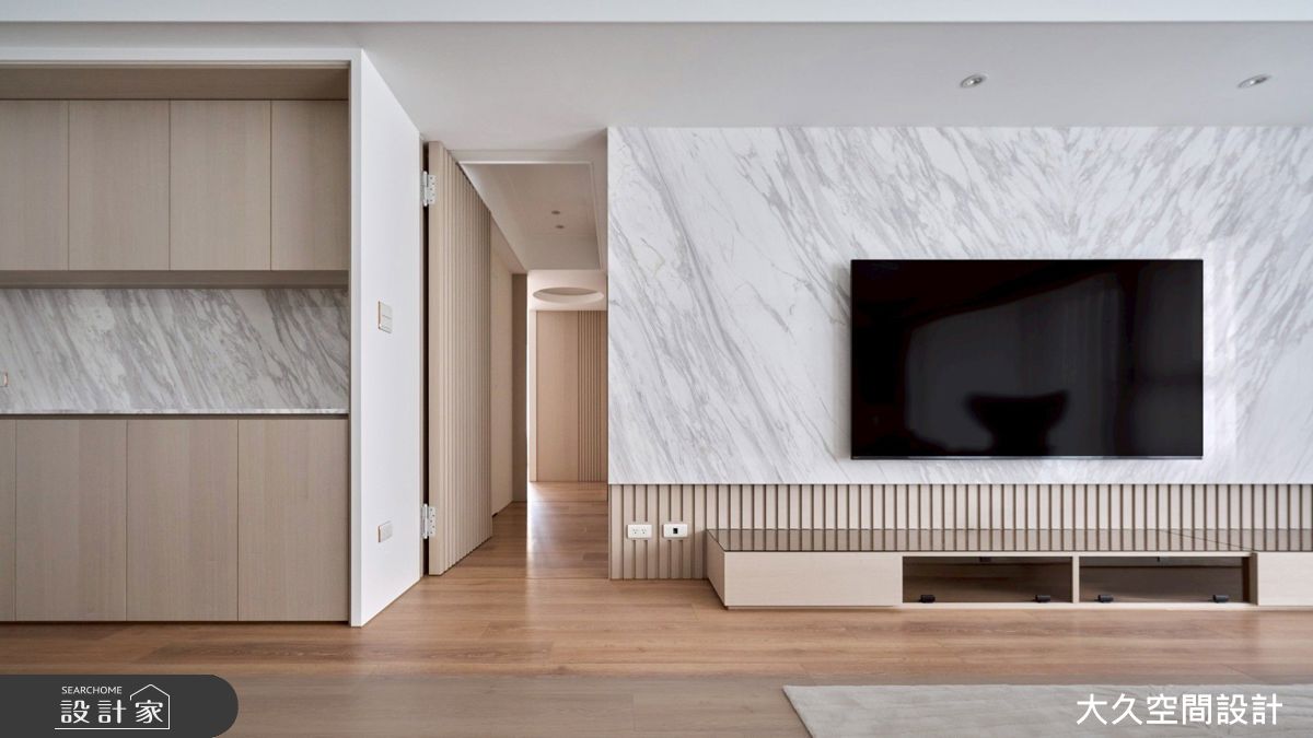 客廳電視牆以石材和格柵鋪陳,並規劃集線收納櫃,保持整潔空間。