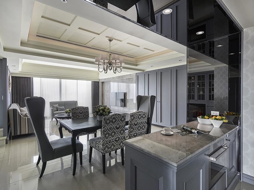 餐廚區以展示壁爐溫暖場域氛圍，牆面則在清淡優雅花紋的潤飾下顯現空間出眾氣質。餐廚交界則以灰鏡鋪設框面，巧妙化解天花樑柱也延伸出空間視覺美感。