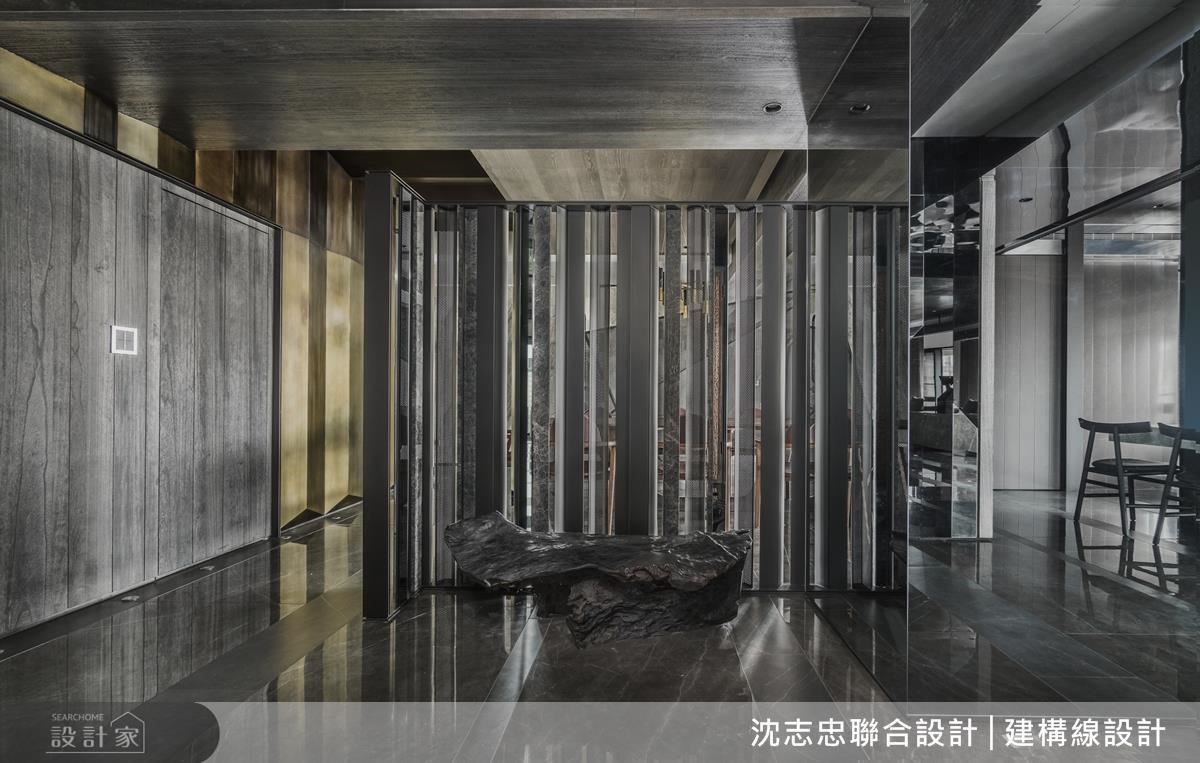 玄關屏風運用鐵件、石材等，以不規則交錯排序，營造穿透性反射與虛實難辨的氛圍，兼具界定場域之作用。