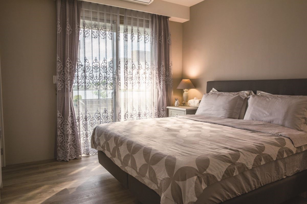 臥室裡舖上木紋質感的地板，伴隨柔和光源與大地色系的寢具搭配，讓睡眠空間更顯靜謐與安定。