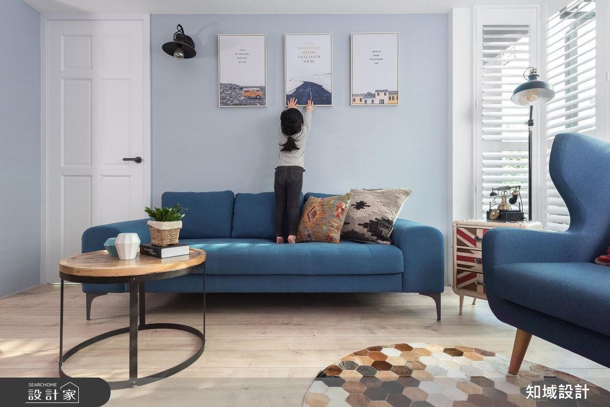 沙發緊靠後方的淺藍色牆面，三幅風景掛畫和壁燈形成質感端景，讓客廳的表情更為豐富。