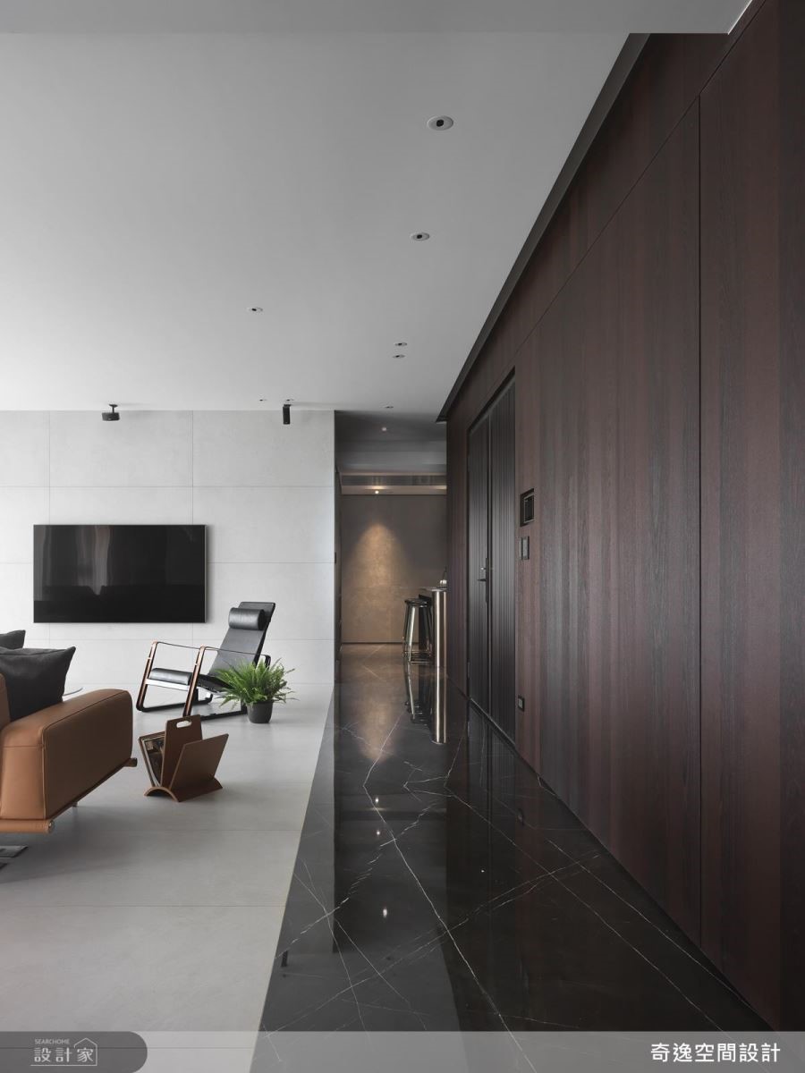 玄關地面以深色大理石對比公領域的淺色磁磚，藉由材質、色彩的鋪陳，巧妙界定空間場域。