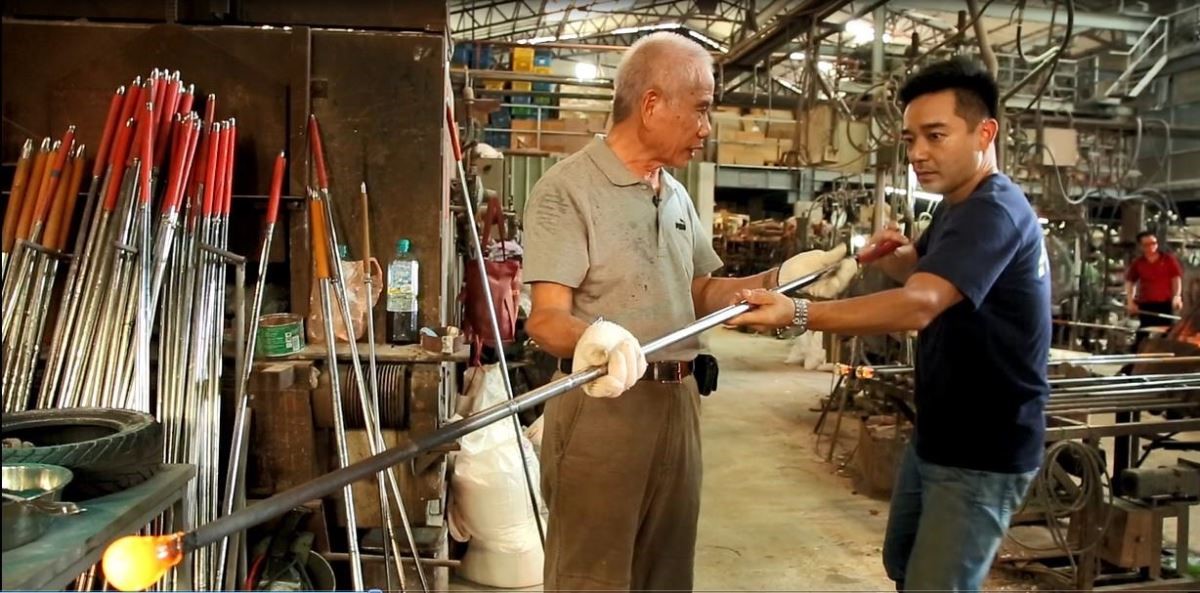 師傅邱文虎教主持人永康為高溫玻璃塑型。