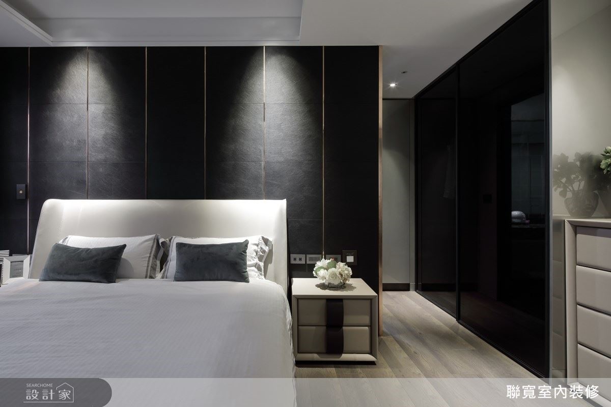 床頭背板的皮革片隱約透出鍍鈦金屬條的光芒，配合上方燈源，很有聚焦效果。