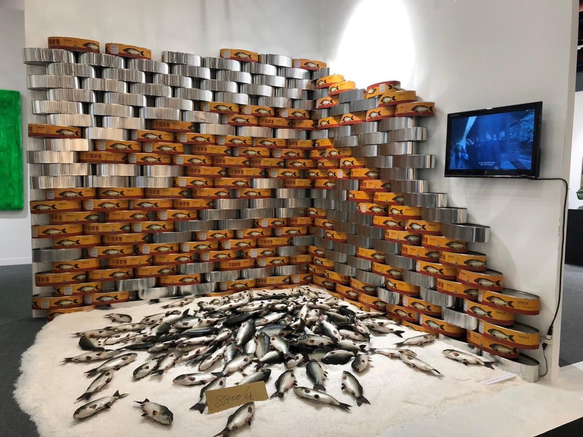宛如把魚販的真實景況搬入展場，極具視覺震撼，每隻鯉魚均附有專屬罐頭收藏盒，也可靠電動擺動尾巴，栩栩如生。凡亞丁丁藝術空間、沈少民。