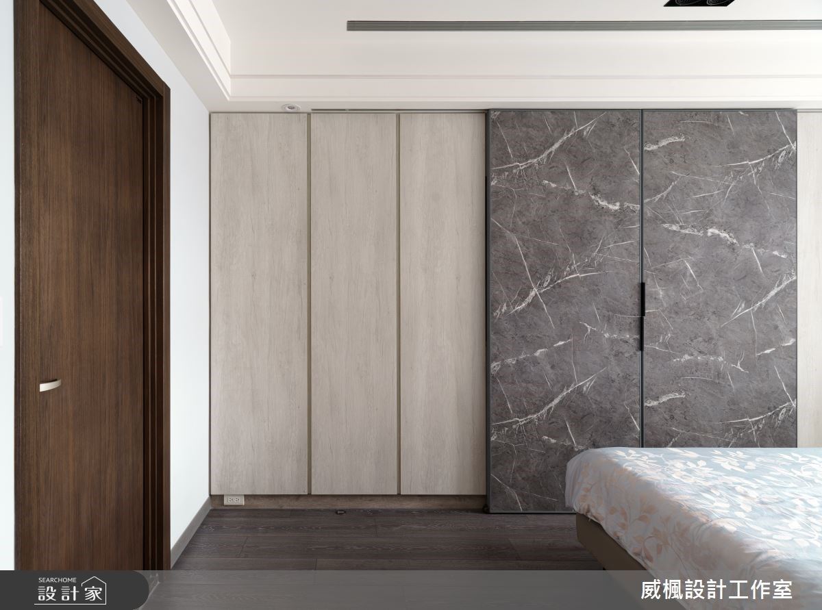 主臥櫃體藉由石紋肌理搭配素色系統櫃，巧妙帶出視覺層次感。