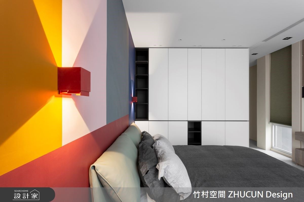 次臥房床頭背牆以飽和色彩搭配壁燈光影，細膩構築活潑空間表情。
