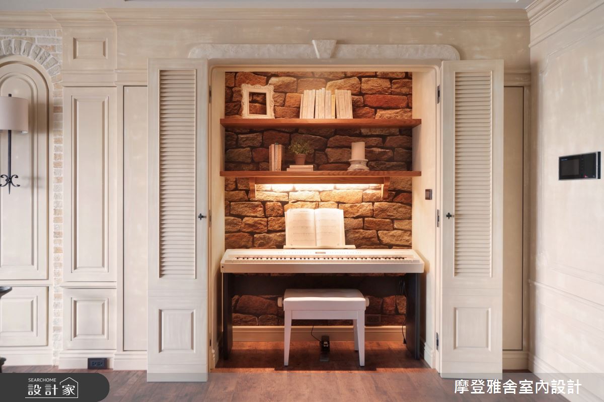 設計師因應屋主的喜好與需求，將電鋼琴隱於門片後方，搭佐立體性十足的文化石壁紙與兩端櫃體，建構充裕收納空間。