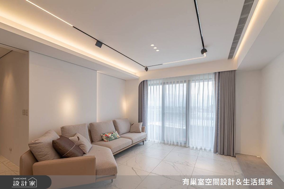 客廳藉由電視牆的配置轉向，使後方的玻璃拉門成為沙發背延伸，成就寬敞舒適的生活空間感。