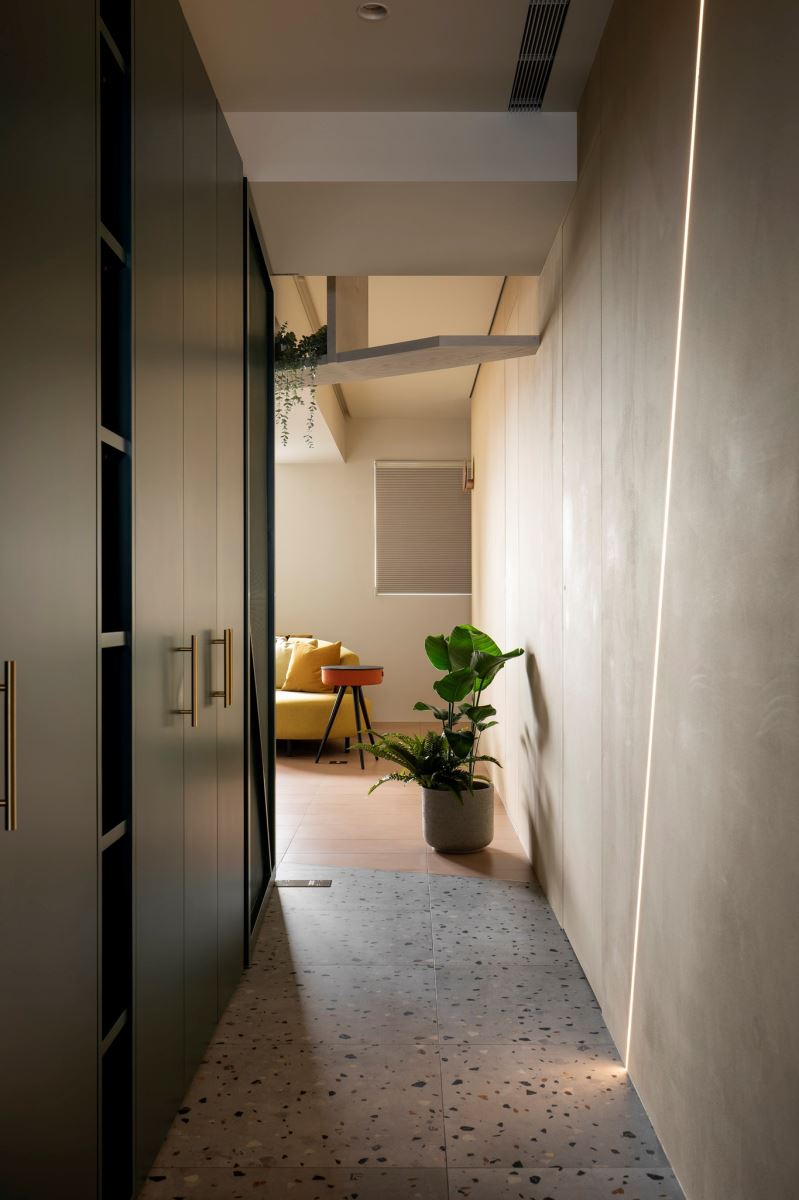 自客廳走進長型廊道則是私密空間，設計師運用線條與櫃體的分割，再搭配抿石地磚，創造出多層次的變化。