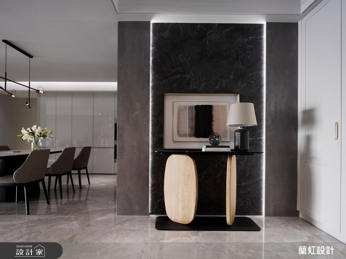 玄關端景牆面使用仿石紋的板材，再利用燈條框出引人入勝的牆面，提升迎賓效果，同時也引導著進屋動線。