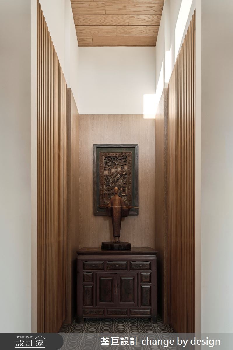 玄關將瓦片重新打磨製成獨一無二的地坪，搭配屋主的古董櫃與藝術品，兩側的木格柵櫃面，呈現一種禪意的氛圍感。