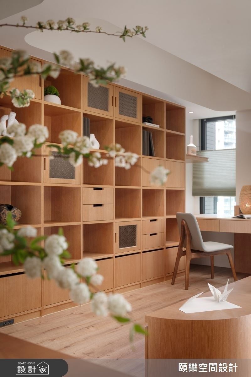 大面書牆增添玻璃海棠窗花、抽屜的形式，可以擺放植栽、書本、收藏品，最後局部加入燈帶的設計，讓書牆成為整個公領域最吸睛的視覺焦點。